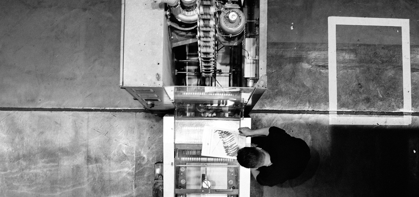Operario revisando una hoja junto a una máquina industrial